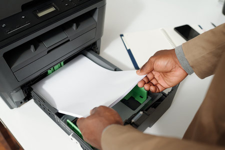 Close-up of hands of young male white collar worker preparing for copying documents while putting...