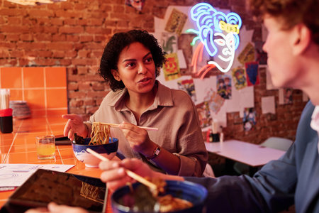 Pretty woman looking at male colleague or her boyfriend at lunch break or date while sitting in...