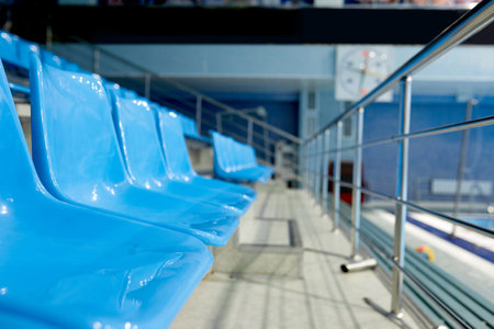 Row of plastic blue seats of empty tribune at large stadium where variety of sports matches, games, trainings and competitions take placeの写真素材