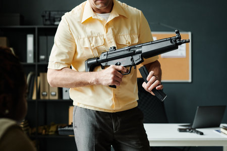 Cropped shot of mature male coach of military training with carbine standing in front of students and explaining weapon structureの写真素材