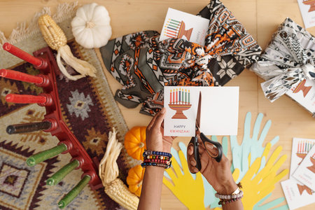 Hands of young woman with scissors cutting part of handmade postcard while creating new one for...
