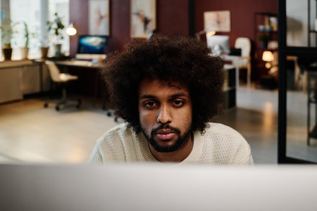 Young male designer concentrating on new project or looking through online data or task points while sitting in front of computer screenの写真素材
