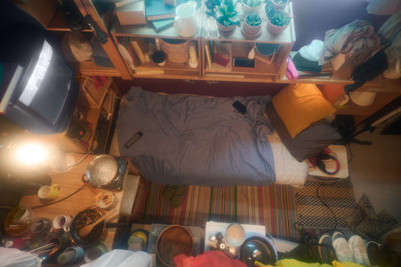 Interior of small apartment or microflat with single bed surrounded by wooden shelves, old TV set,...