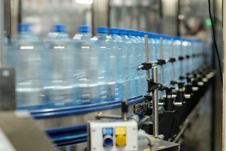 Part of factory robotic conveyor belt with row of moving capped plastic bottles containing filtered...