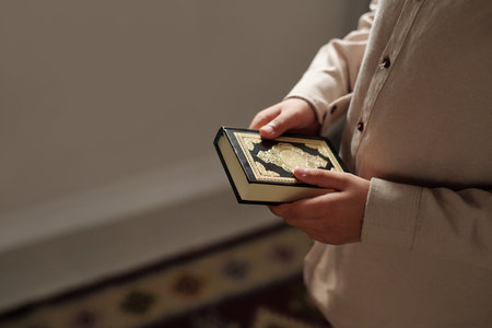 High angle view shot of unrecognizable kid holding holy Quran book in hands, copy spaceの写真素材