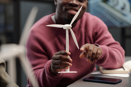 Cropped shot of young successful African American businessman touching model of windmill while presenting his business projectの写真素材