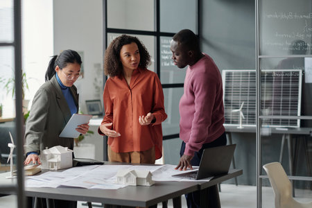 Young confident African American female architect looking at male colleague while discussing points...