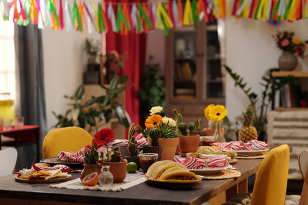 Tasty homemade snacks and other treats standing on served festive table decorated by domestic flowers growing in flowerpotsの写真素材