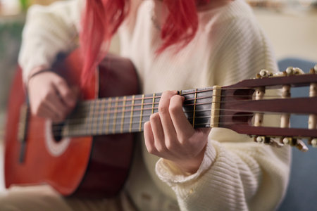 Close-up of young talented female musician playing acoustic guitar in front of camera while performing and recording her new songの写真素材