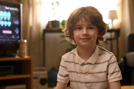 Portrait of Caucasian teenage boy sitting near retro TV with vintage video game on its screen,...