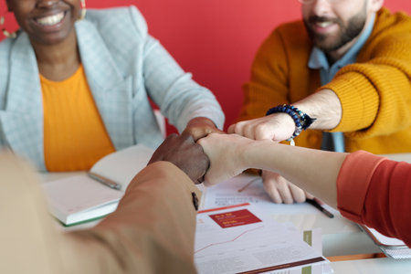 Close-up shot of hands of multi-ethnic business team giving fist bump during office meeting, showing unity and collaborationの写真素材