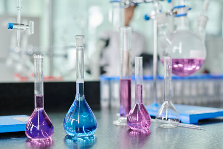 Group of transparent glassware with blue and purple liquid substances standing in row on workplace of modern chemist or clinicianの写真素材