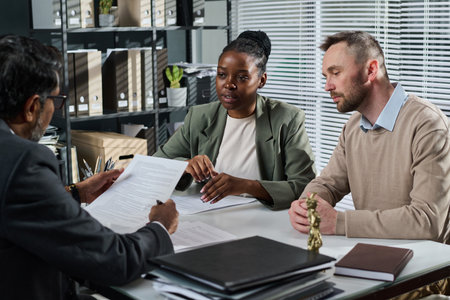 Young intercultural business people looking at mature male solicitor or notary with contract in...