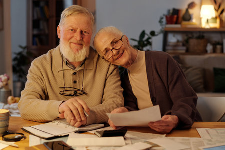 Couple of happy late bloomers in casualwear looking at camera while smiling woman in eyeglasses keeping head on husband shoulderの写真素材