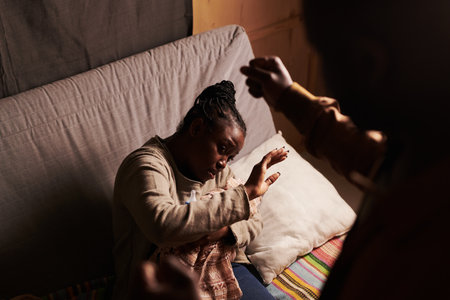 High angle of young helpless woman with newborn baby in hands defending from angry husband keeping fist over herの写真素材