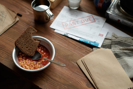 Close-up of bowl containing baked beans with slice of rye bread on rustic wooden table surrounded by...