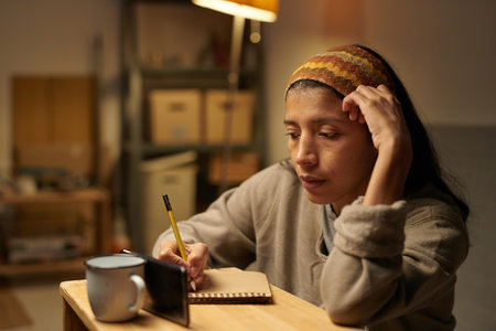 Woman wearing knitted headband and comfortable sweater sitting at wooden table with hot drink and...