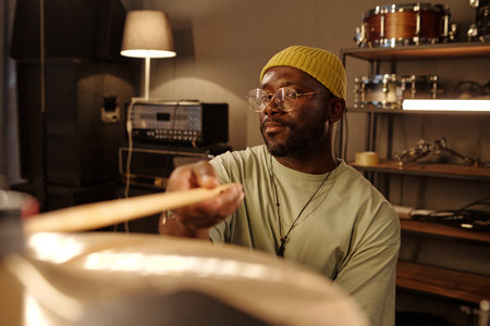 Man playing drums in professional recording studio, showing concentration and passion wearing yellow...