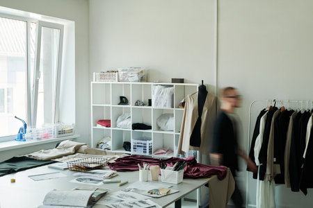 Corner of spacious modern atelier or workshop of fashion designers with variety of supplies on...