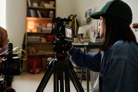 Woman operating professional video camera on tripod, capturing scene in indoor setting with...