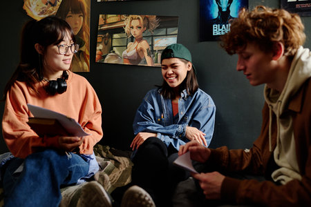 Group of young adults engaging in conversation about various artworks displayed on walls. Casual...