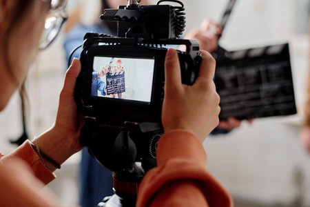 Close-up view of camera display showing clapperboard during film shoot. Person holding camera with...