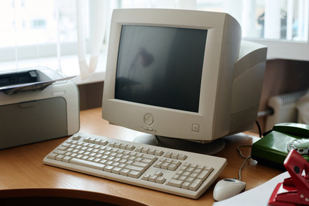Vintage computer setup including CRT monitor, keyboard, and printer on wooden desk, creating...