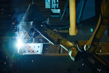 Automated welding robot creating sparks in industrial environment focusing on precision. Strong blue...