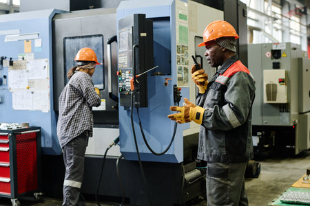 Workers in an industrial setting overseeing machinery operation and coordination. Using...