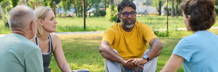 Banner of smiling mature man in activewear sitting on mat between diverse people and listening to...