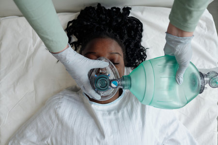 Close up of person giving medical oxygen assistance to patient lying in bed focusing on the...