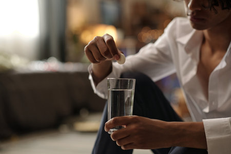 Cropped shot of unrecognizable guy putting effervescent pill into glass of water while suffering from hangover after boozeの写真素材
