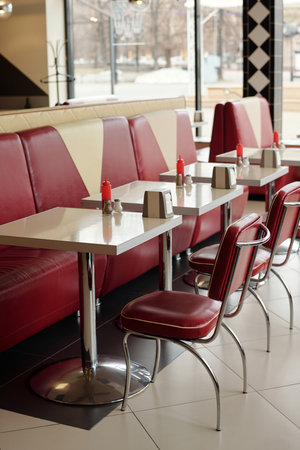 Classic retro diner setting featuring red booths and silver tables creating a nostalgic atmosphere with modern touches Expectedly quiet with empty tables and clean surfacesの写真素材