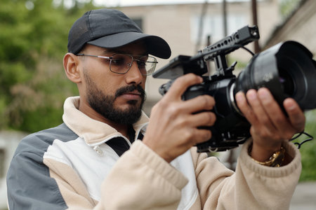 Close-up of a man filming with professional camera, showcasing dedication and refinement in...