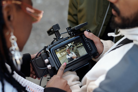 People examining footage on professional camera screen during outdoor shoot. Focus on digital...