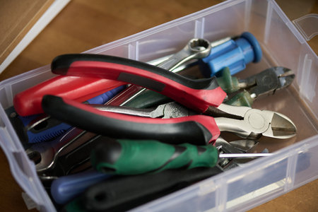 Pliers, wrench, screwdriver and other secondhand DIY handtools in plastic container standing on...