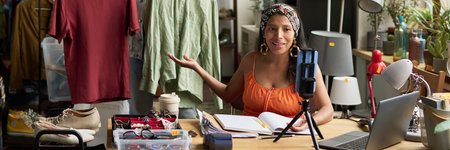Banner of happy young female owner of thrift shop looking at smartphone screen while making vlog...