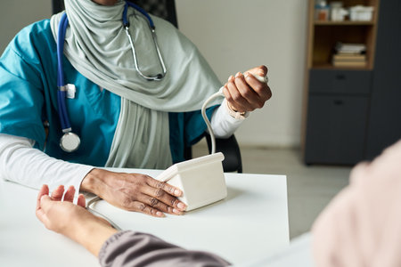 Muslim medical professional wearing stethoscope, holding patients hand, performing consultation in clinic settingの写真素材
