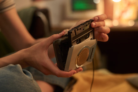 Hands handling vintage cassette tape player with focus on the device Capturing retro technology with nostalgic surroundings and home environmentの写真素材