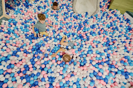 High angle of spacious playground with abundance of colorful balloons and cheerful adorable children playing among themの写真素材