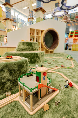 Toy cars and railway station on the floor covered with green carpet on spacious playground in modern leisure centerの写真素材