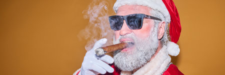 Santa Claus wearing sunglasses and smoking cigar against an orange backgroundの写真素材