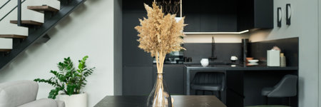 Modern interior showcasing a sleek kitchen and living room with tall grass arrangement in glass vase...