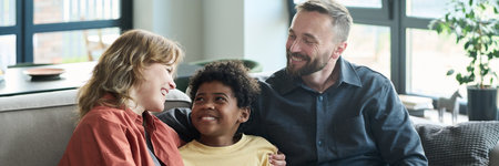 Family members cuddling on a cozy couch in bright room. They are smiling, spending time together,...
