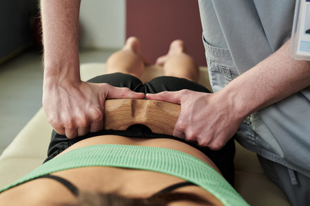 Close-up of chiropractors hands performing spinal adjustment on patient lying face down on treatment...