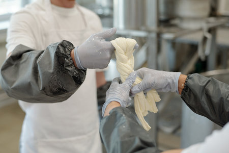 Hands of chefs stretching mozzarella cheese with precision in professional kitchen, showcasing...