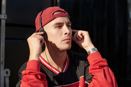Person wearing casual clothes while listening to music using headphones in an outdoor setting....