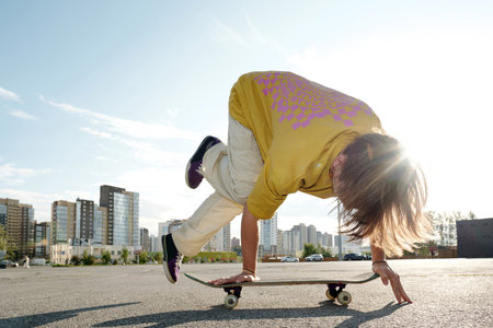 Person skateboarding on urban street performing tricks near buildings during daytime with cloudy sky in backgroundの写真素材