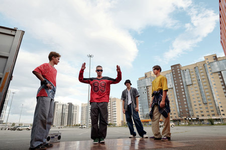 Group of young men standing on urban street surrounded by tall buildings. Each guy expressing...