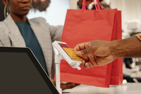 Hand of young male shopper applying credit card to payment terminal screen while paying for new...